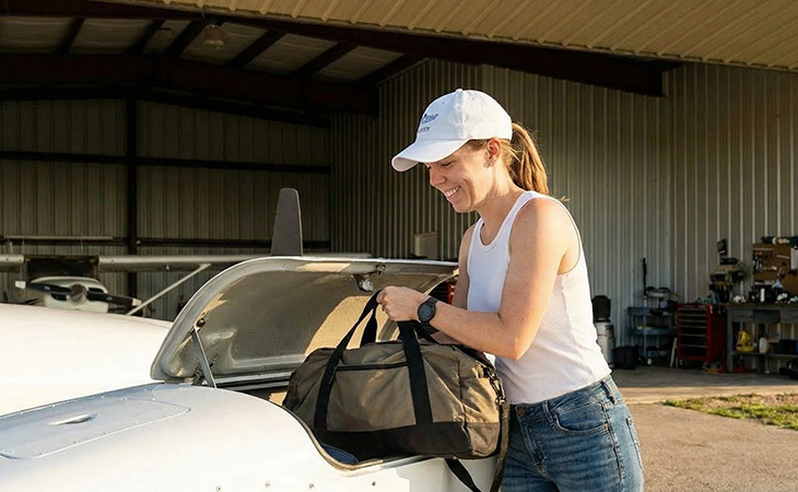 Girl wearing white aviation baseball cap, dad hat, packing her aircraft