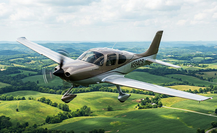 Cirrus aircraft caught mid air over green fields