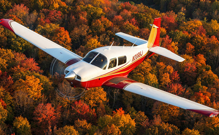 Mooney M20J aircraft cruising mid-air, high-performance single-engine airplane for private aviation