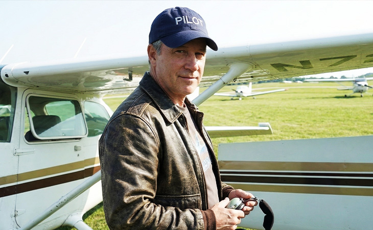 Pilot standing beside his aircraft wearing a pilot hat, private aviation lifestyle