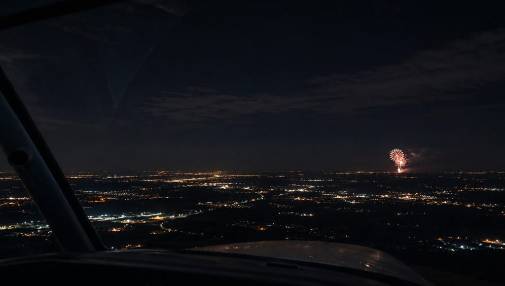 Pilot's view of fireworks over city during night flight.