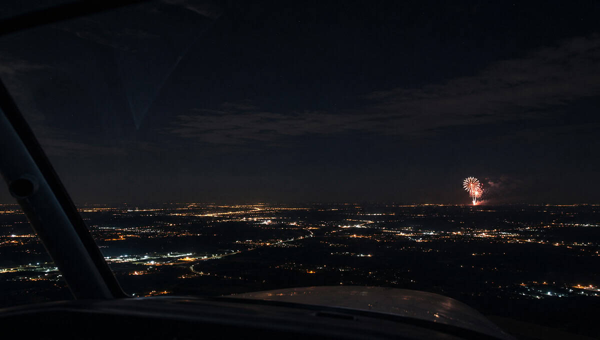Pilot's view of fireworks over city during night flight.